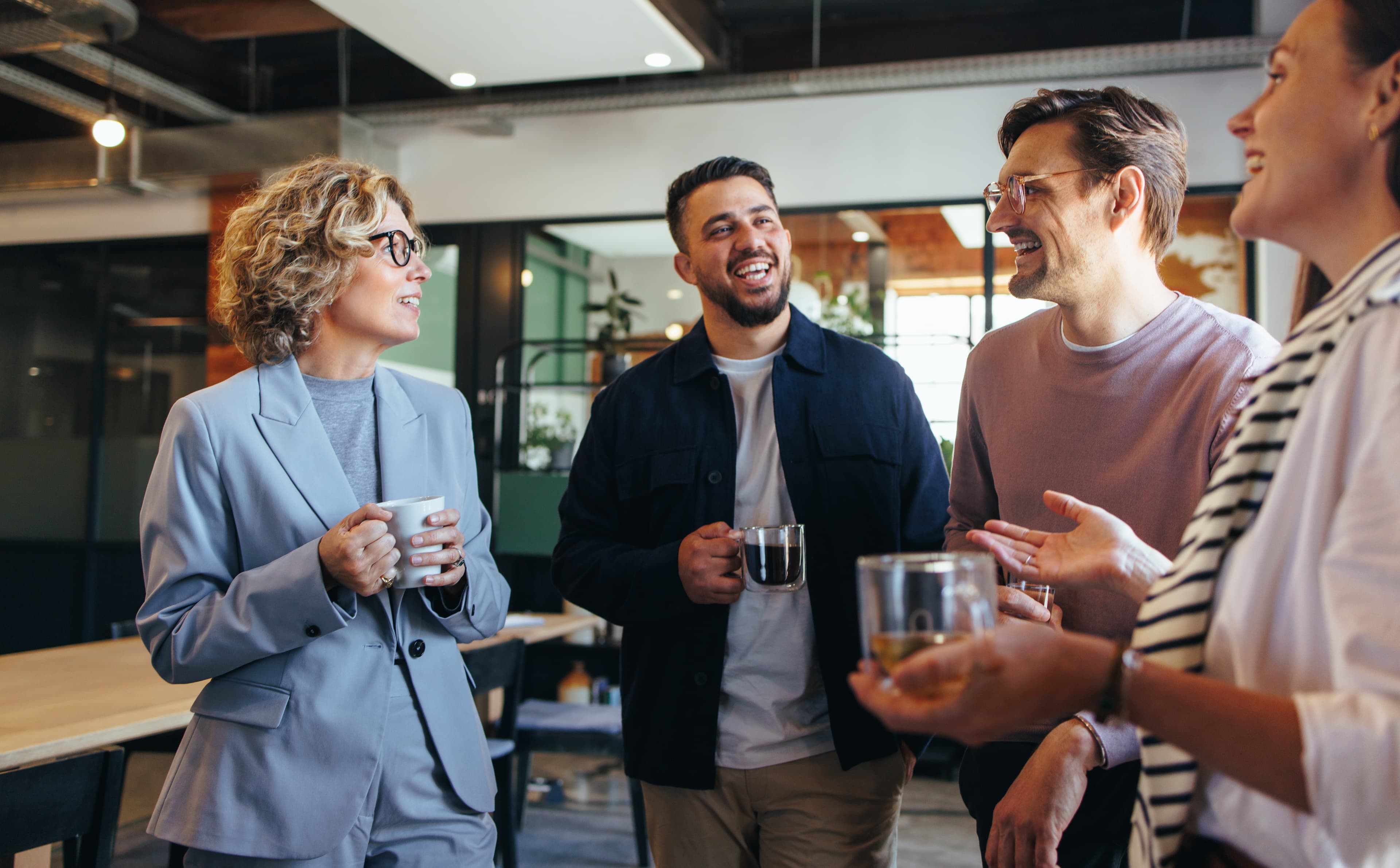 Colleagues talking over coffee at work, where auto-enrolment applies